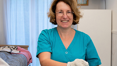 Portrait de Véronique, Aide-Soignante à domicile au chevet d'une patiente en situation de handicap